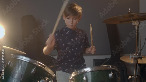 Creative kids. Young musician. Kid playing drums in the music produciton studio. A blonde hair young boy in a fancy shirt learning how to play songs.