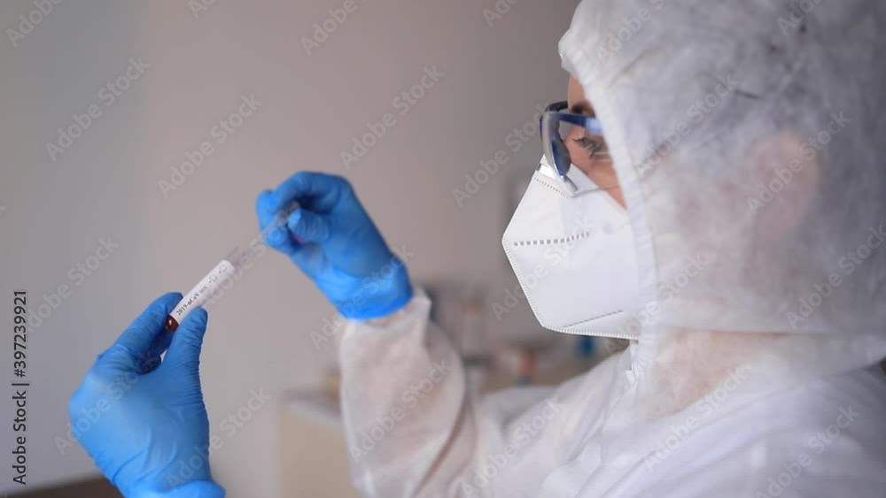 Slowmotion scene of medicine woman wearing protective gear, holding a test tube for 2019-nCoV analyzing. Coronavirus blood test concept. Selective focus Slowmotion scene of medicine woman wearing protective gear, holding a test tube for 2019-nCoV analyzing. Coronavirus blood test concept. Selective focus