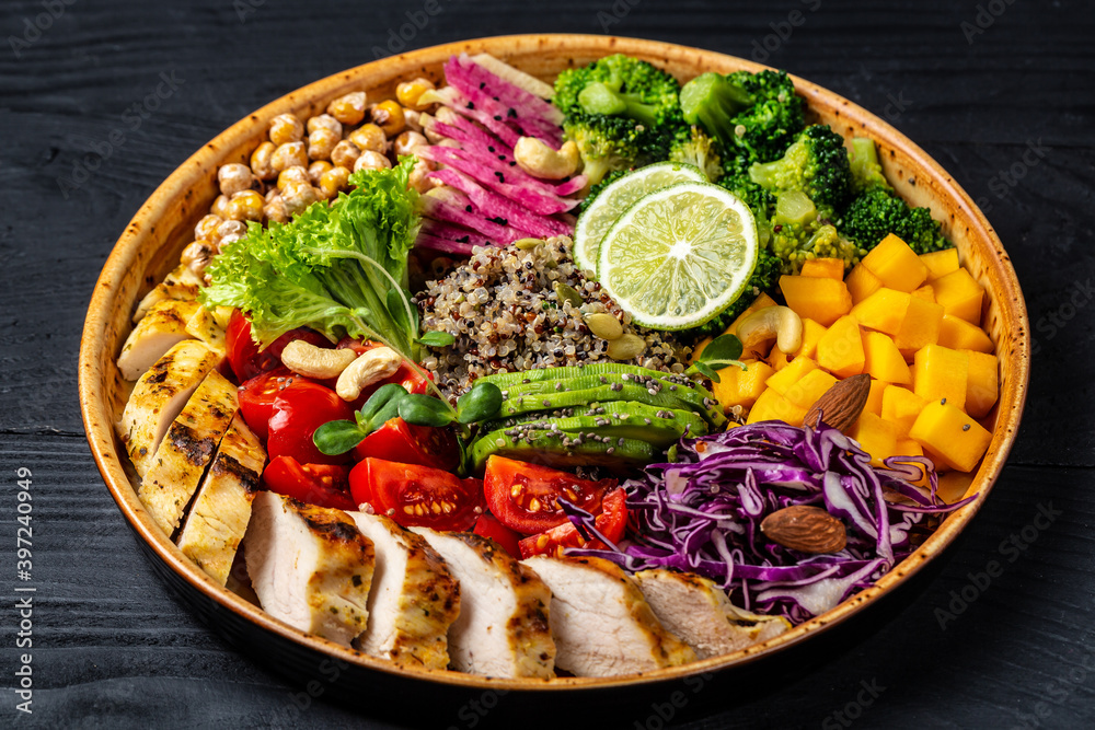 Fresh salad. Bowl with fresh raw vegetables, chicken fillet, quinoa, avocado, chickpea, watermelon radish and nuts. Healthy food. buddha bowl