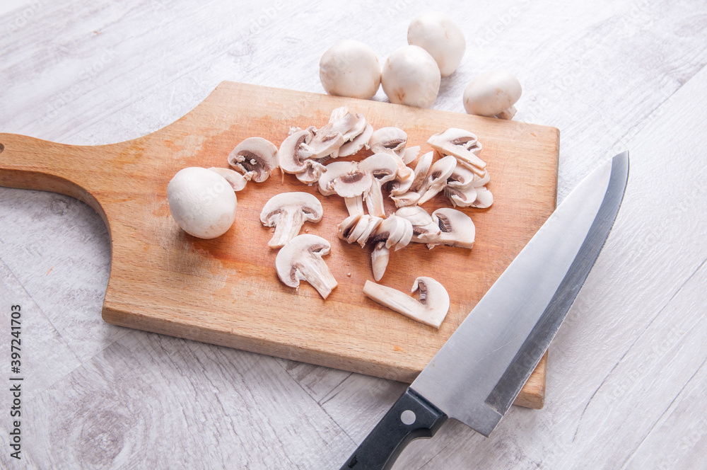 Sliced mushrooms on a chopping board with kitchen knife Sliced mushrooms on a chopping board with kitchen knife