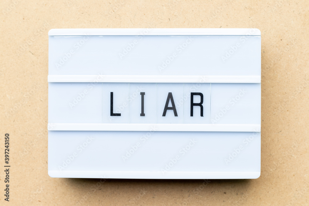 White lightbox with word liar on wood background White lightbox with word liar on wood background