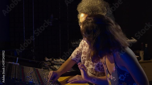 Music recording studio. Creative people. Hispanic man and woman working in the sound studio. Brunette curly latin couple is producing songs and having a good time. 