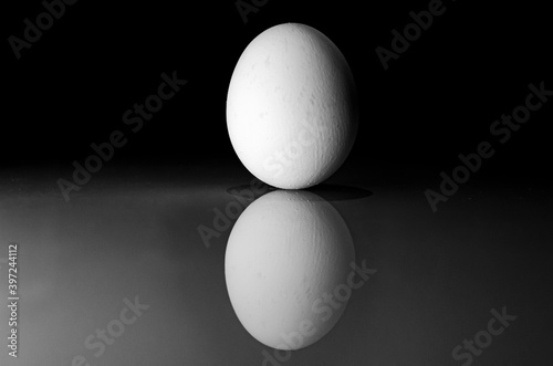 White egg on the table with a reflection in the dark