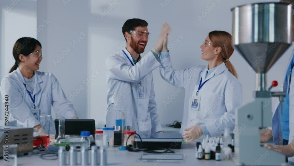 Happy cooperative science team of medical workers successfully developing vaccination or medicine giving high-five applauding celebrating victory in laboratory. Happy cooperative science team of medical workers successfully developing vaccination or medicine giving high-five applauding celebrating victory in laboratory.