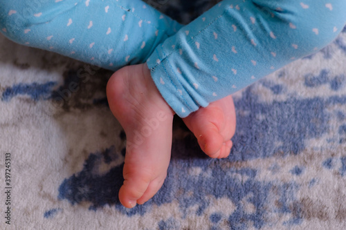 Close up of caucasian newborn baby girls feet, sleeping baby on the carpet with selective focus