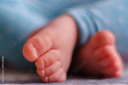 Close up of caucasian newborn baby girls feet, sleeping baby on the carpet with selective focus