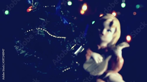 Natale vintage, bambola bambina che suona vicino l'albero di Natale con luci a intermittenza colorate. photo