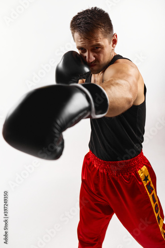 sporty man in black boxing gloves punching isolated on white background. © producer