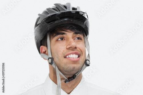 Close-up of Indian businessman wearing cycling helmet while looking away against gray background © moodboard
