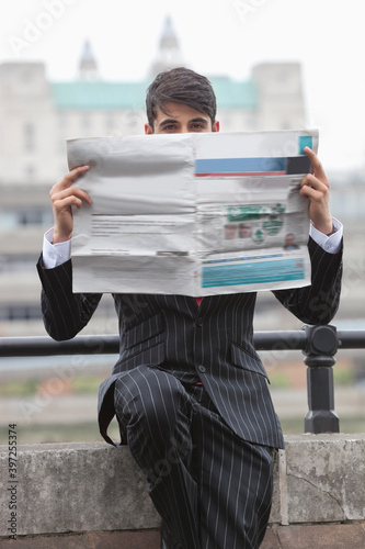 Portrait of a businessman holding newspaper in front of his face with St. Paul's Cathedral in the background photo