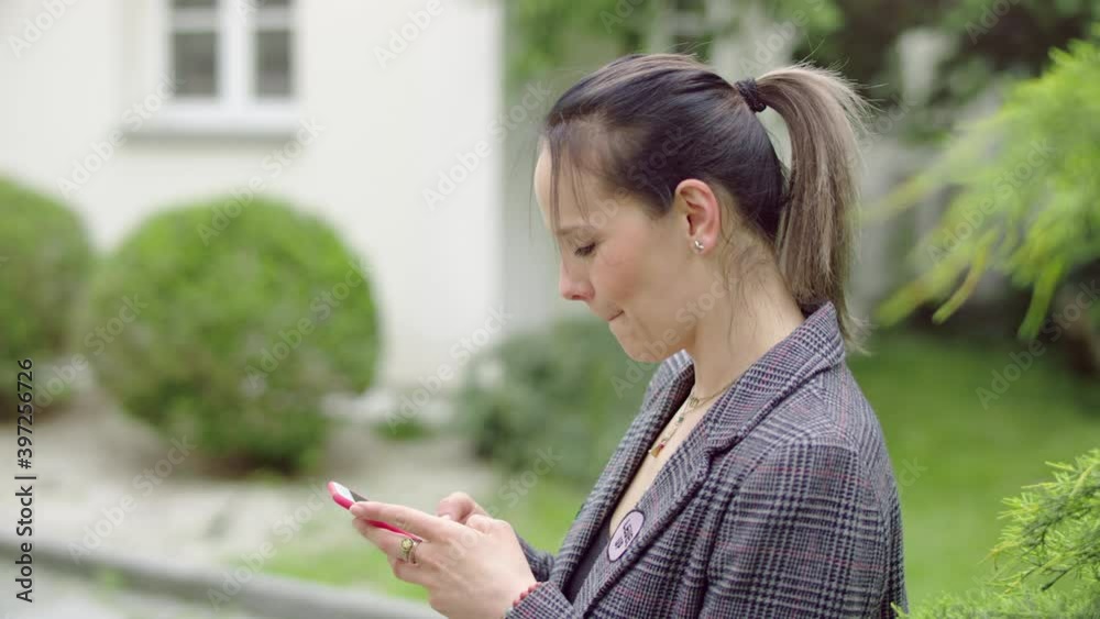 A young and happy woman is grinning from ear to ear while she's chatting with her frinds on her mobile. A young and happy woman is grinning from ear to ear while she's chatting with her frinds on her mobile.