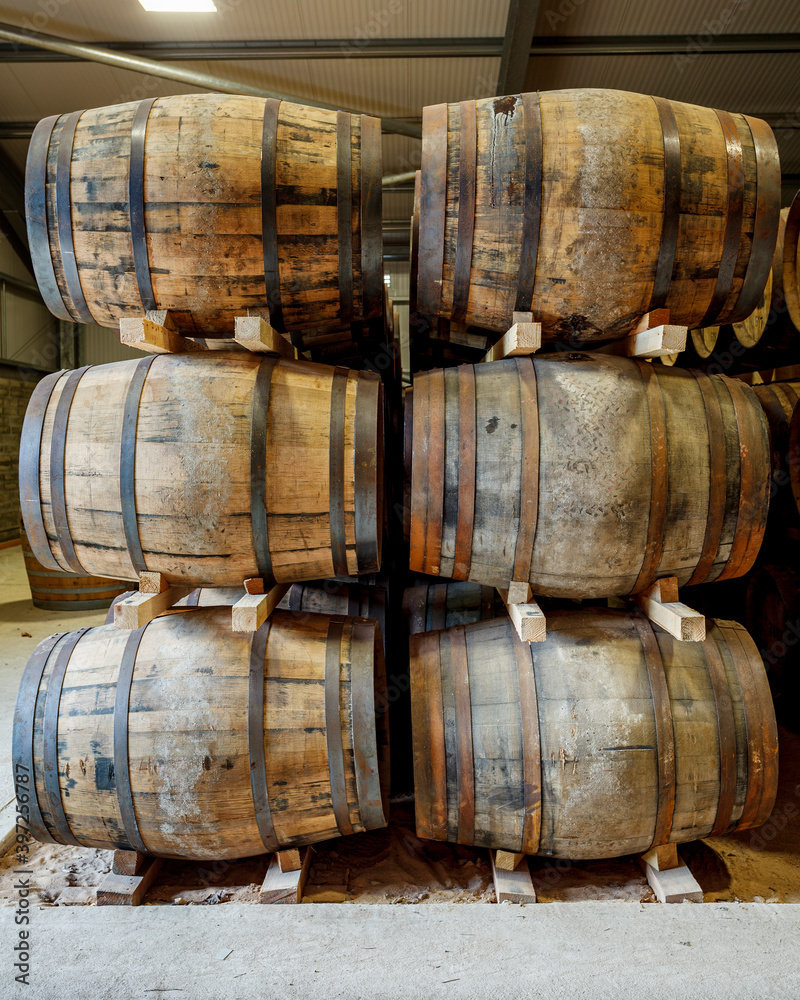 A stack of 6 traditional full whisky barrels, set down to mature, in a large warehouse A stack of 6 traditional full whisky barrels, set down to mature, in a large warehouse