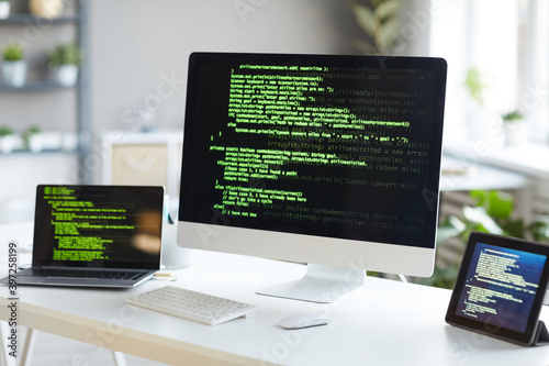 Image of computer monitor with computer programmer laptop and digital tablet on the table at office