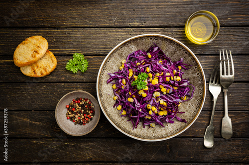 Fresh coleslaw salad made of shredded red and white cabbage and corn on dark wooden background, top view