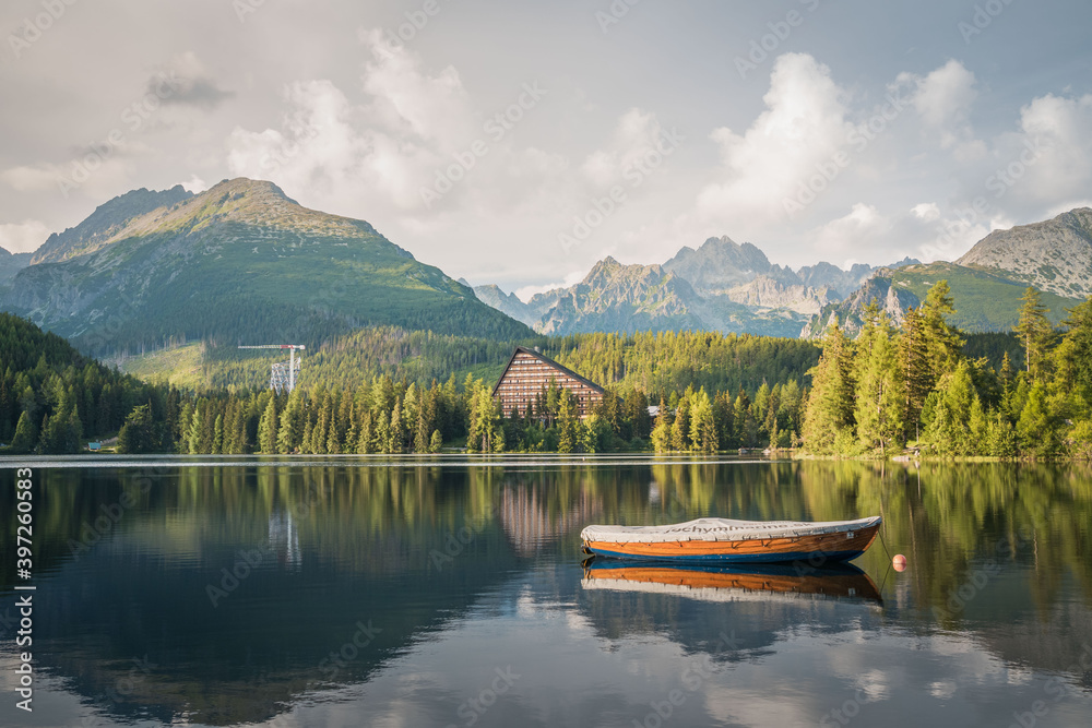 Mountain lake Strbske Pleso with small boat in the foreground in National Park High Tatras. Slovakia, Europe. Late summer evening at lakeside.