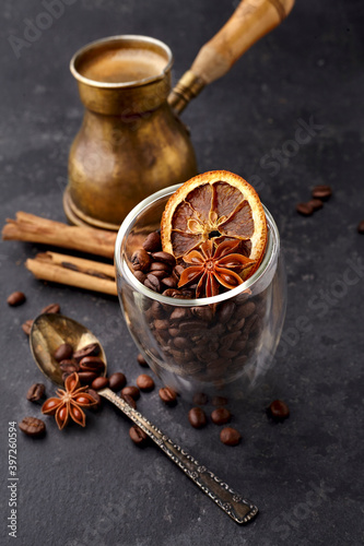 Coffee with coffee beans, anise, dry orsnge  and cinnamon on black background.