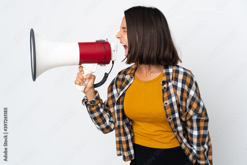 Naklejka premium Young latin woman isolated on white background shouting through a megaphone to announce something in lateral position