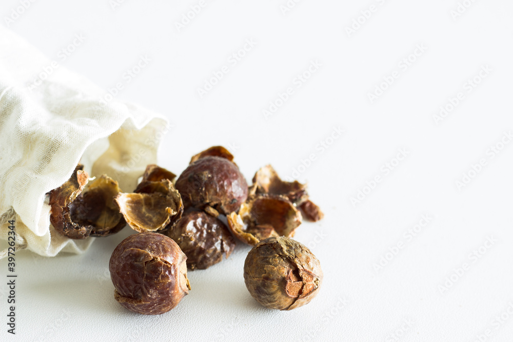 soap nuts falling out of linen bag on white background soap nuts falling out of linen bag on white background