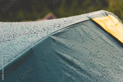 Dew drops on green tourist tent. Waterproof fabric rain, test of bad weather