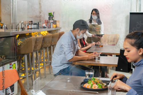 Asian male using mobile phone and waiting for food in cafe restaurant.