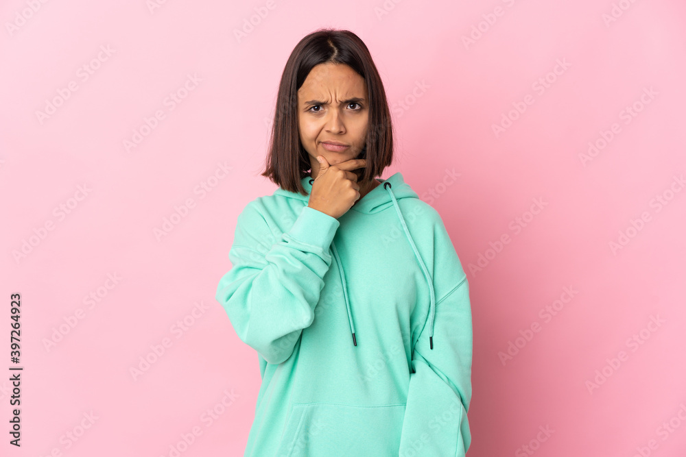 Young latin woman isolated on pink background having doubts and with confuse face expression Young latin woman isolated on pink background having doubts and with confuse face expression
