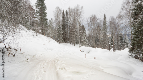 Snow covered country road in winter forest © Koirill