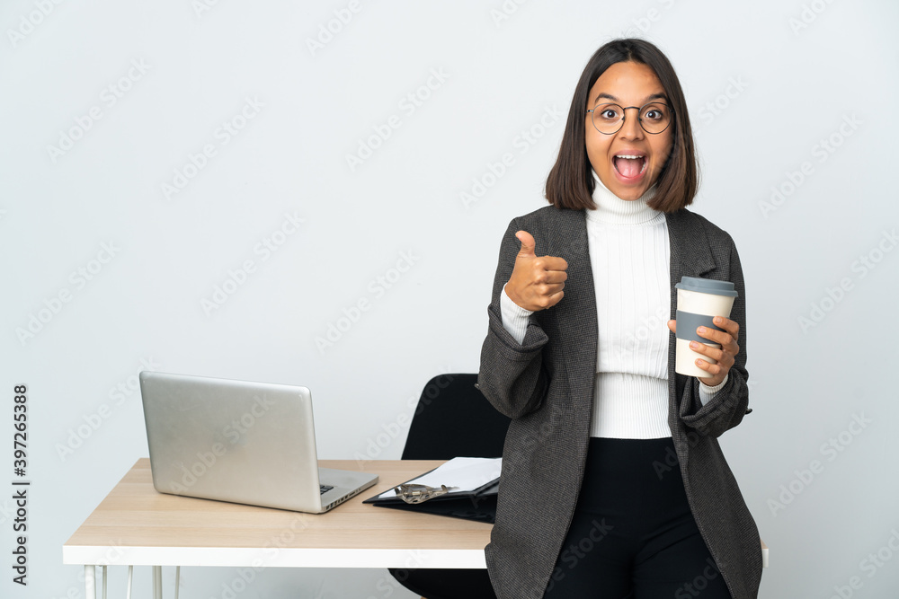 Young latin business woman working in a office isolated on white background showing ok sign and thumb up gesture Young latin business woman working in a office isolated on white background showing ok sign and thumb up gesture