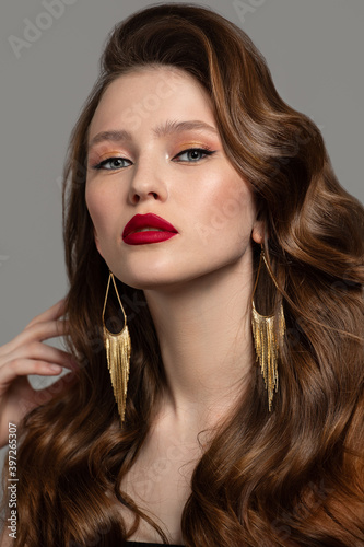 Beautiful woman with perfect makeup and hairstyle. red lips and gold earrings