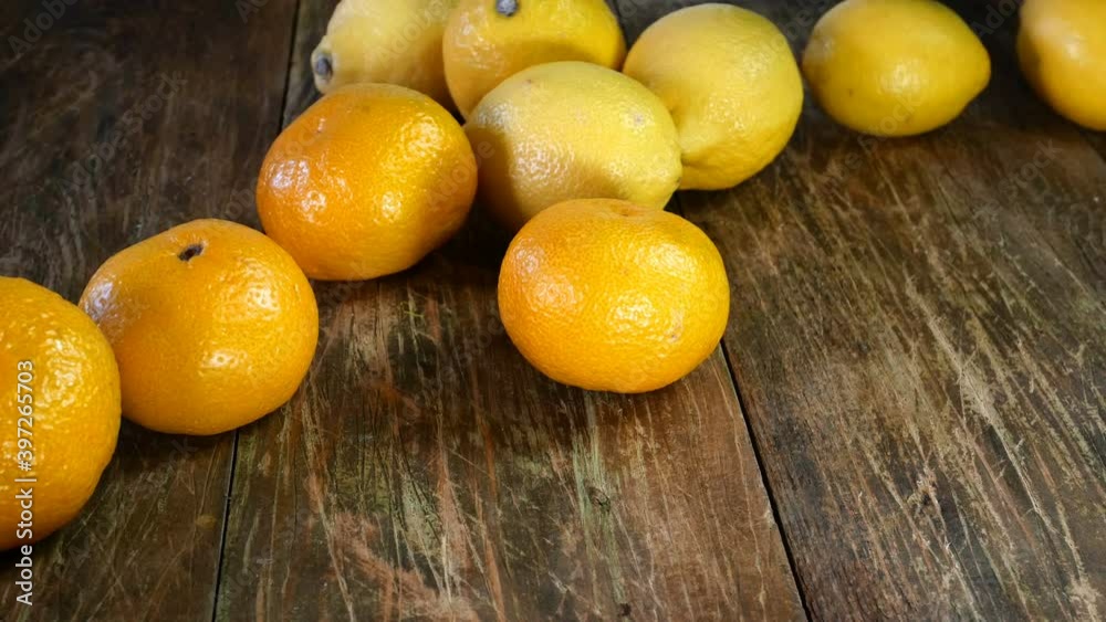 Cooks job. Different citrus fruit throwing from paper bag onto wooden table. Tangerine and lemon. Close-up. Cooks job. Different citrus fruit throwing from paper bag onto wooden table. Tangerine and lemon. Close-up.