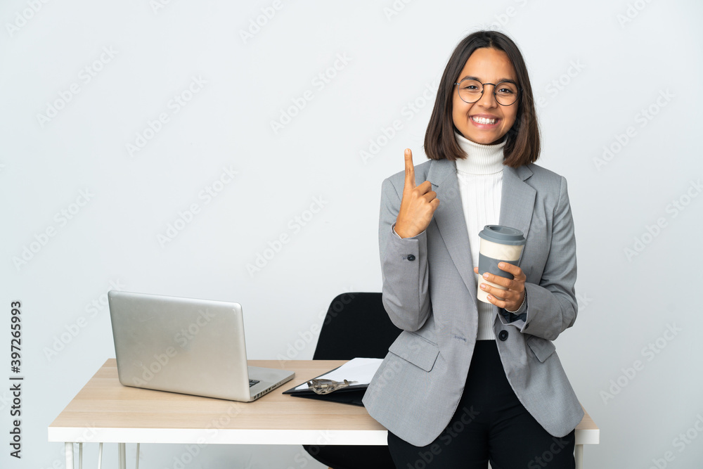 Young latin business woman working in a office isolated on white background pointing up a great idea Young latin business woman working in a office isolated on white background pointing up a great idea