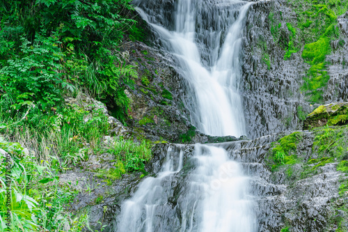Fototapeta Naklejka Na Ścianę i Meble -  Atmospheric view of waterfall on river in rainforest. Swift stream among rocks and green moss.