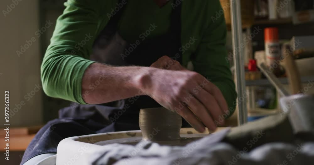 Mid section of male potter creating pottery on potters wheel at pottery studio Mid section of male potter creating pottery on potters wheel at pottery studio