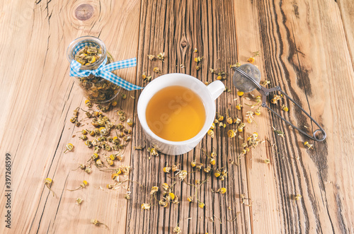 Chamomile tea with dried petals on wooden table photo