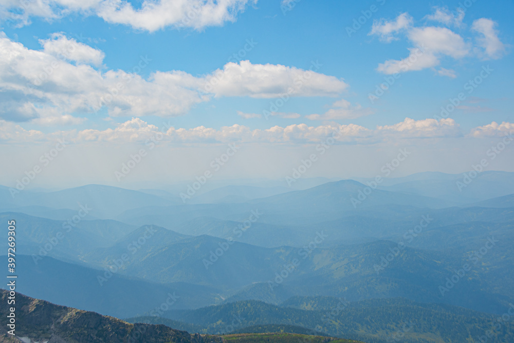 Rocky ridge on horizon under blue cloudy sky. Mountain valley for travel. Adventure travel, tourism and conservation concept.