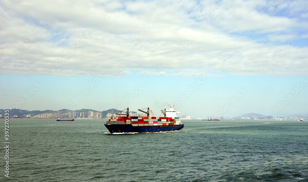 Fully loaded, geared container ship departing port of Xiamen, China. 