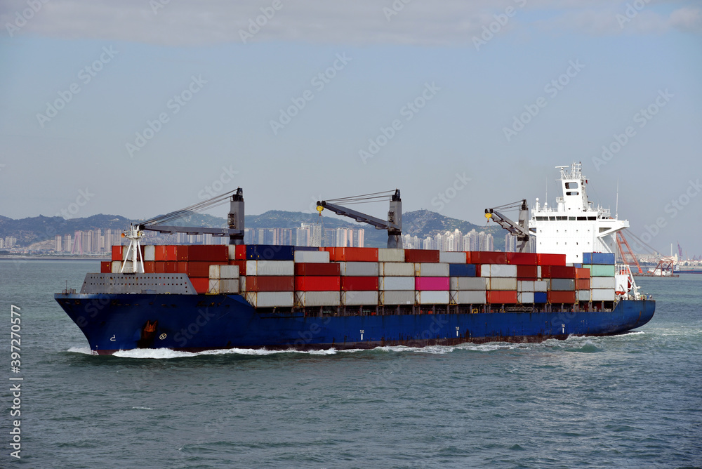 Fully loaded, geared container ship departing port of Xiamen, China. Fully loaded, geared container ship departing port of Xiamen, China.