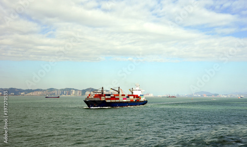 Fully loaded, geared container ship departing port of Xiamen, China. 