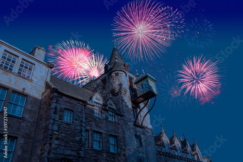 Celebratory fireworks for new year over lock Canongate Toll Booth Clock of Edinburgh from royal mile in Scotland during last night of year. Christmas atmosphere. 