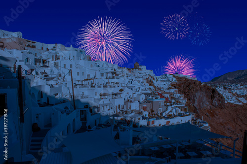 Celebratory fireworks for new year over Oia town cityscape at Santorini island in Greece. Aegean sea during last night of year. Christmas atmosphere