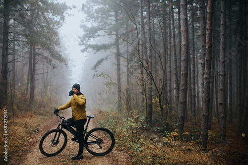 Fototapeta Naklejka Na Ścianę i Meble -  Young man taking a brake during biking through autumn forest