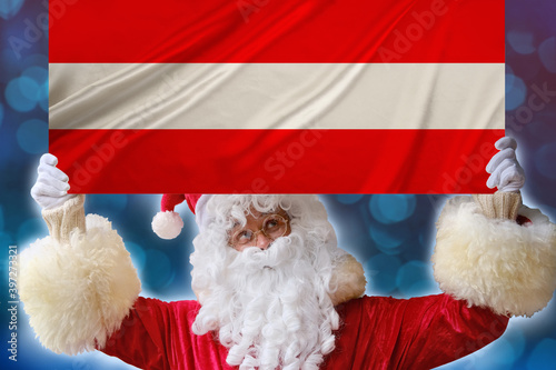Santa Claus with a beard holds a beautiful colored national flag of the state of Austria on fabric, concept of tourism, New Year and merry Christmas, economic and political prospects