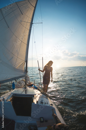 A girl in a dress stands on a sailing yacht © zhukovvvlad