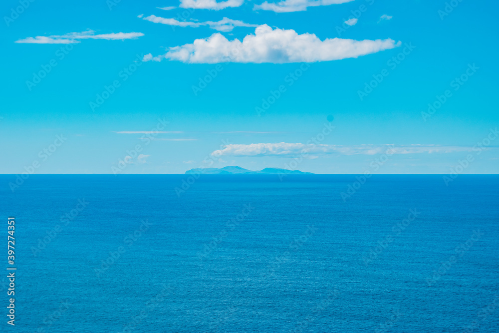 Obraz premium Turquoise Atlantic Ocean with silhouette of São Jorge island on the horizon and clouds, gradient colors - Azores PORTUGAL