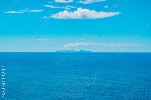 Turquoise Atlantic Ocean with silhouette of São Jorge island on the horizon and clouds, gradient colors - Azores PORTUGAL