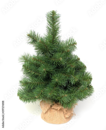 Artificial Christmas tree in a jute bag on a white background.