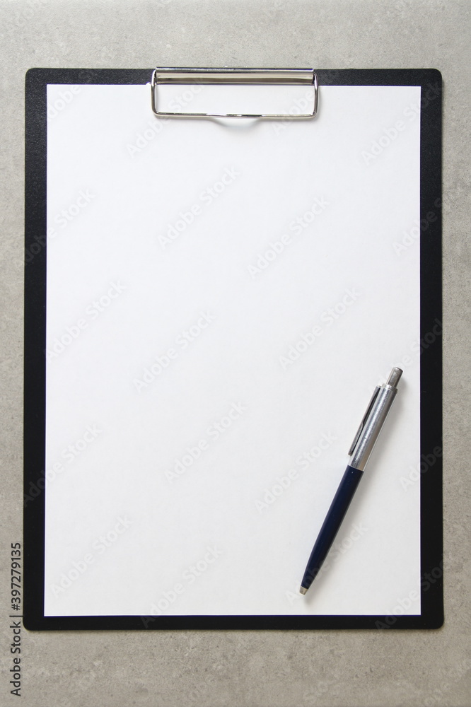 Template of white paper with a ballpoint pen on light grey concrete background in a black tablet with a clip. Concept of new idea, business plan and strategy, with empty space for text Template of white paper with a ballpoint pen on light grey concrete background in a black tablet with a clip. Concept of new idea, business plan and strategy, with empty space for text