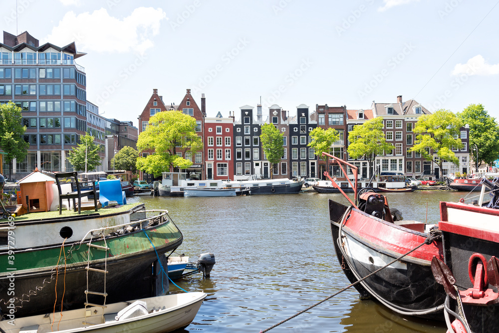 Obraz premium View of Amstel River in the city center of Amsterdam. Seen from Roeterseiland with canal houses, canal boats, Schutssluis.