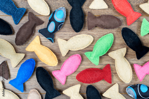 Colored felt fish for cats on wooden background