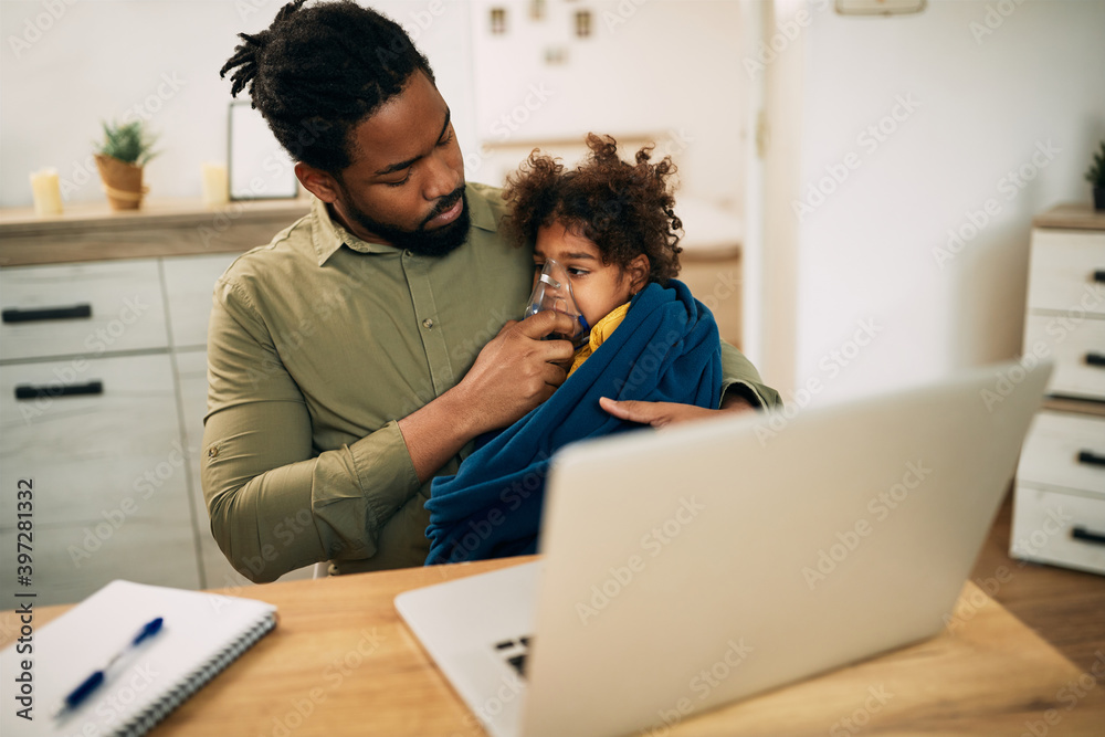 Black father using nebulizer while giving his daughter inhaling therapy at home. Black father using nebulizer while giving his daughter inhaling therapy at home.