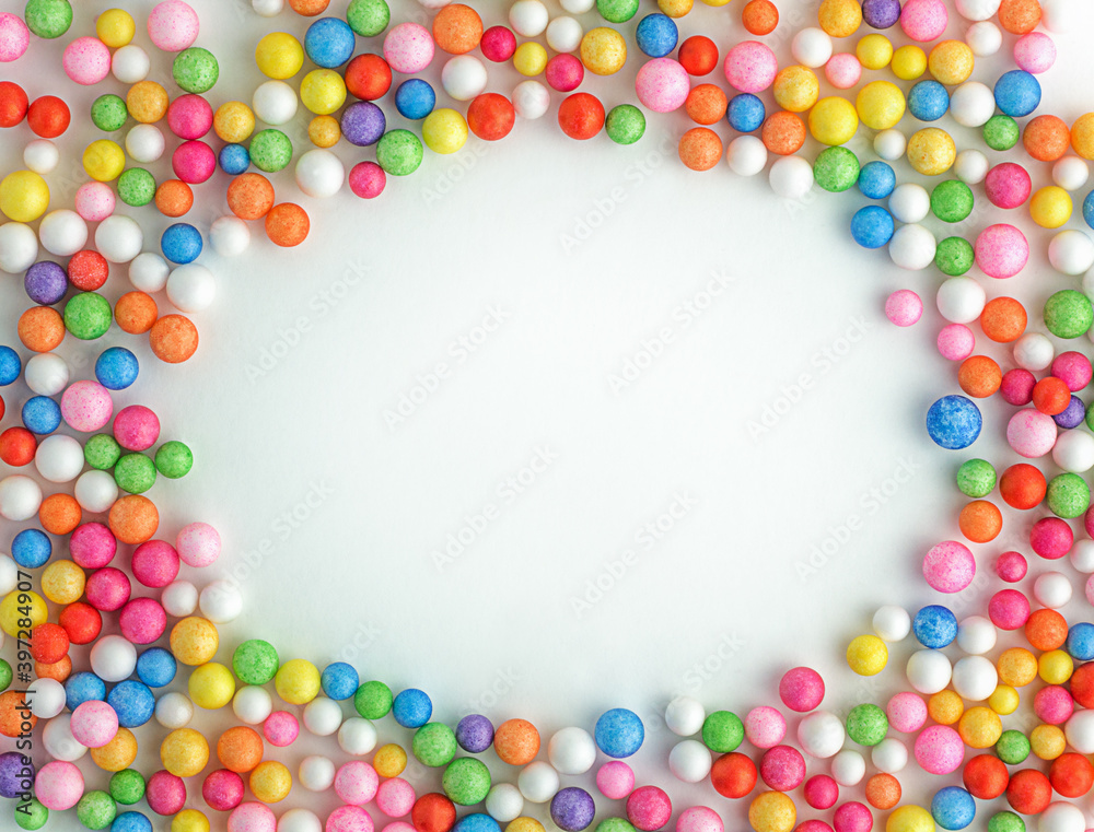 Colorful bright candy on a white background spread out in the form of a wreath frame. Top view of small balls with copy space for text Colorful bright candy on a white background spread out in the form of a wreath frame. Top view of small balls with copy space for text